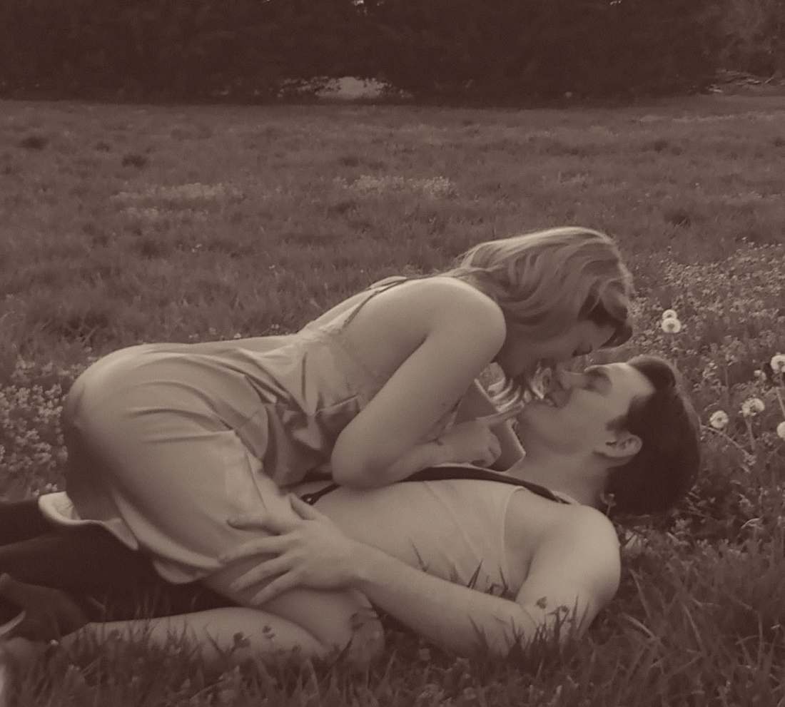 Bonnie and Clyde embracing in a field of wildflowers (sepia)