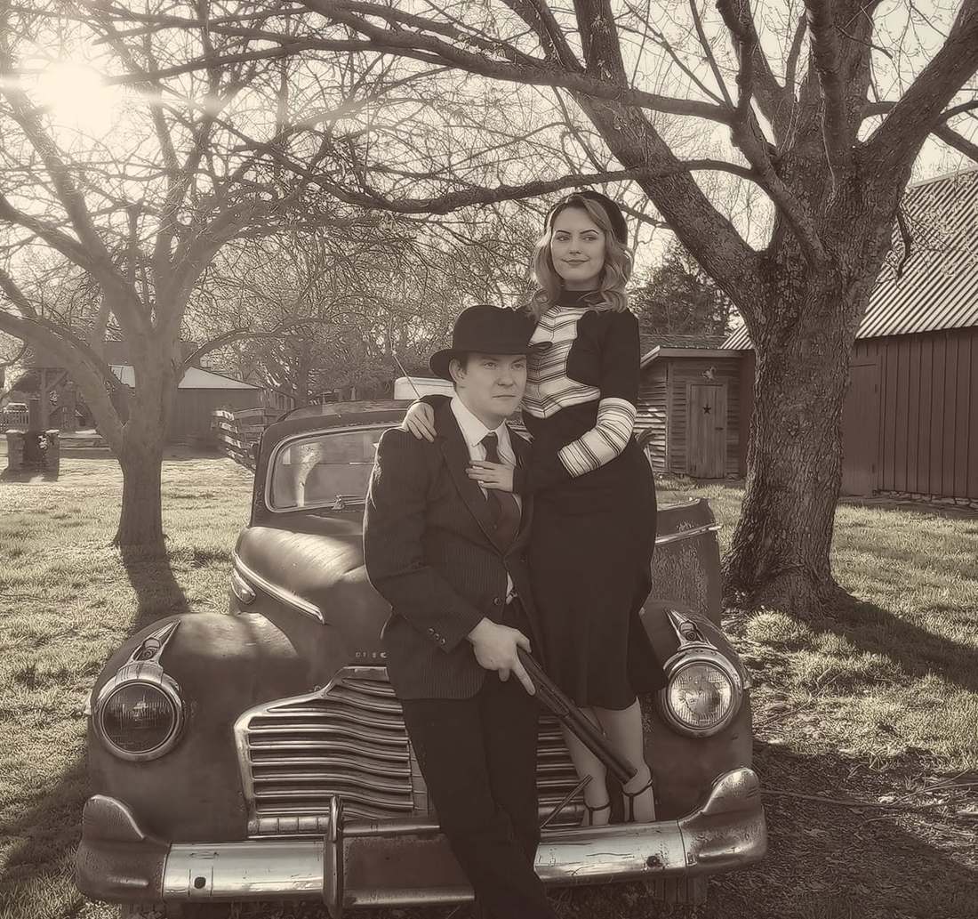 Bonnie and Clyde posing together in front of the vintage Buick (sepia)