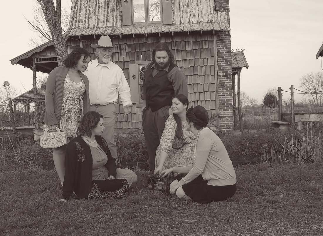 Cast members gathered around a picnic basket outside the shingled cottage (sepia)