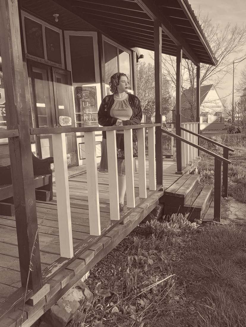 Bonnie leaning on the rail of the old store porch (sepia)