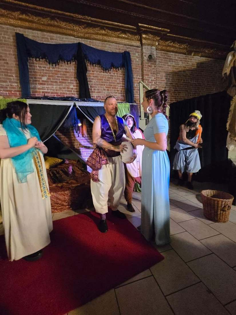 The prince and princess talk in the marketplace, a basket at their feet