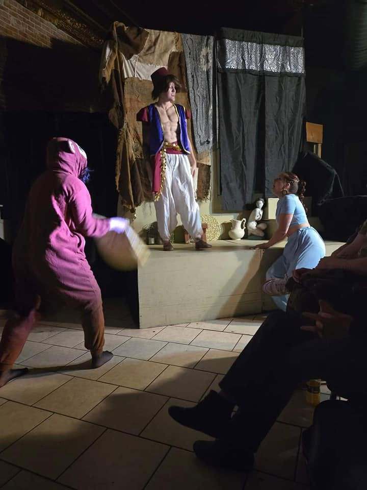 A performer in a magenta monkey suit charges across the stage in a comic Twisted bit