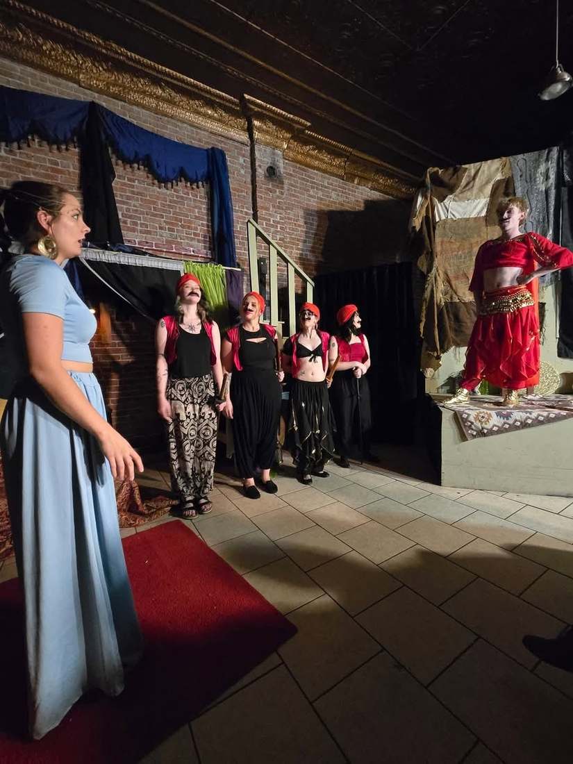 The ensemble watches as a dancer in red performs from the platform in Twisted
