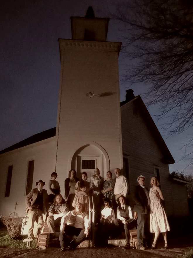 The Bonnie & Clyde company posed on the steps of the tall white church at night (sepia)