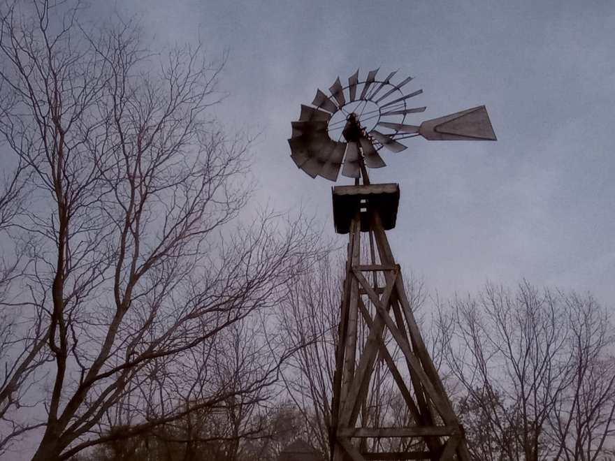 A farm windmill silhouetted against a dusky sky