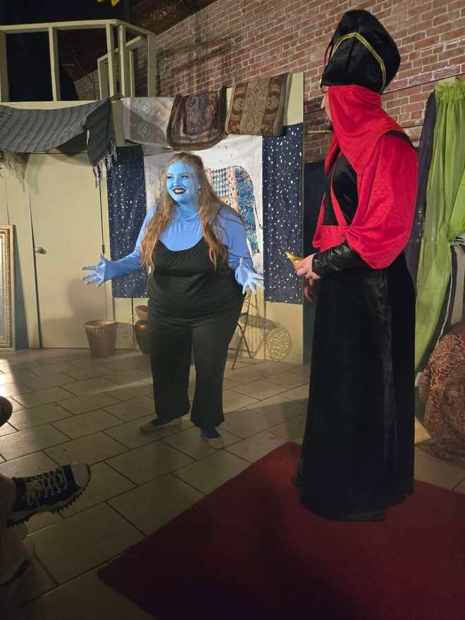 The blue Djinn spreads her arms wide before the Vizier in Twisted
