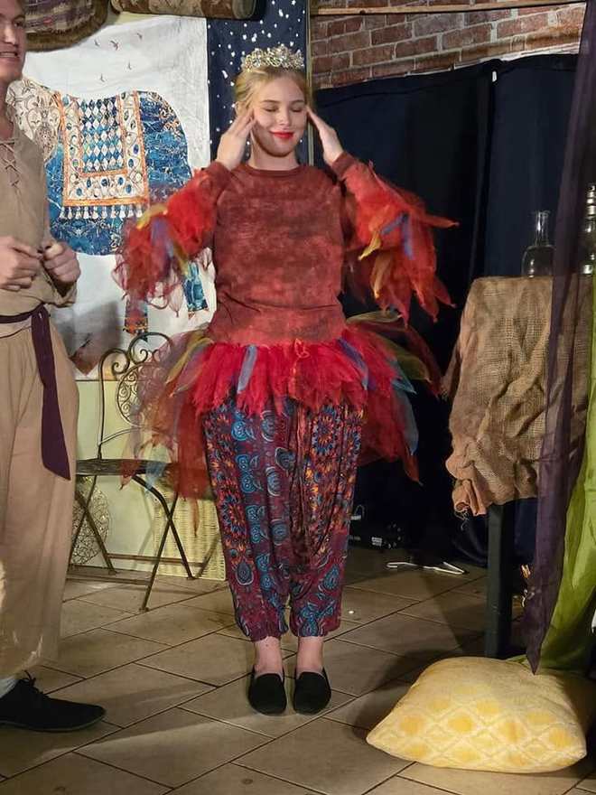 Iago in a red feathered costume and crown on the Twisted set
