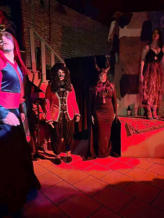 Visiting villains — a captain in a red coat and a horned queen — bathed in red light in Twisted