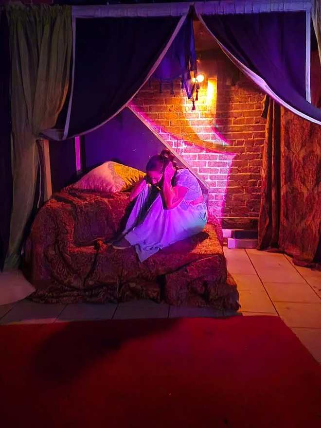 The princess curls up on the palace couch, head in her hands, under purple light