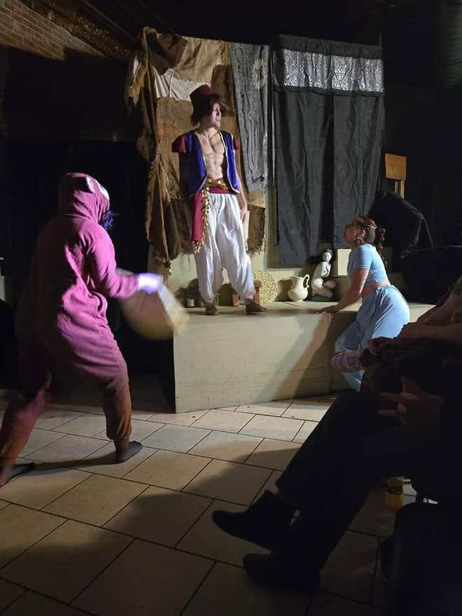 A performer in a magenta monkey suit charges across the stage in a comic Twisted bit