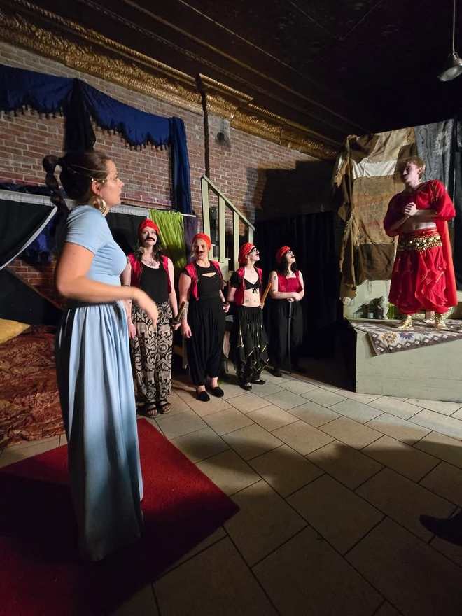 The princess faces a line of red-capped ensemble players in Twisted