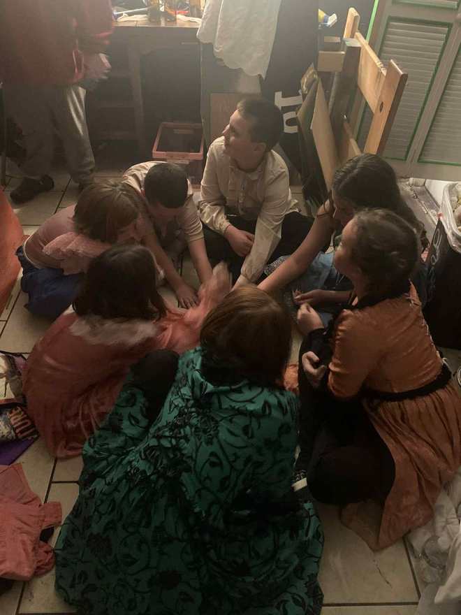 The young Frankenstein cast sits in a circle on the floor backstage before the show