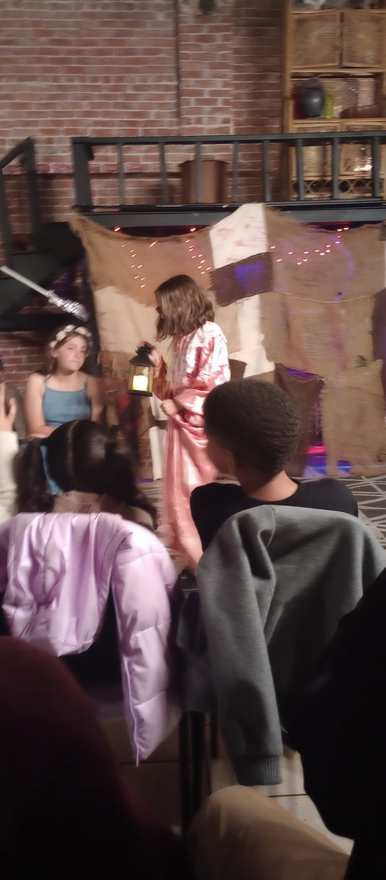Two young performers share a lantern-lit moment on stage
