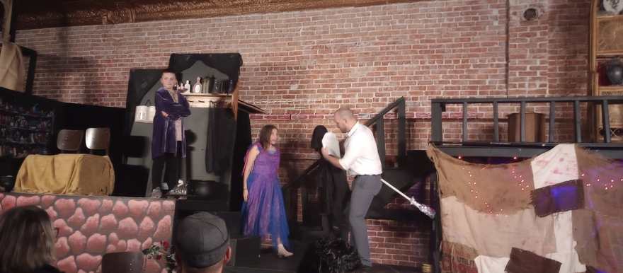 Performers gather by the laboratory set as a scene unfolds on the stairs