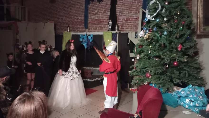 The Nutcracker presents himself to the white-gowned performer as the cast in black looks on