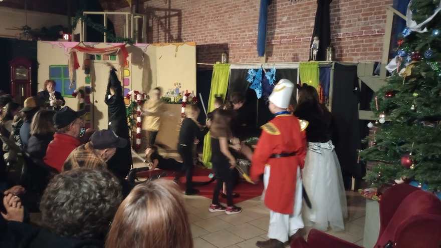 The Nutcracker, seen from behind in his red uniform, watches the cast move across the stage