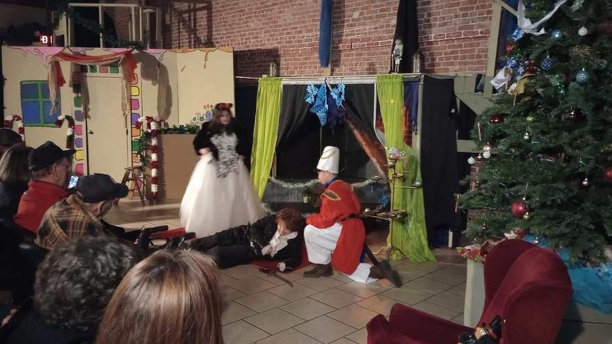 A performer lies on the floor after the battle as the Nutcracker kneels beside them and the white-gowned performer looks on
