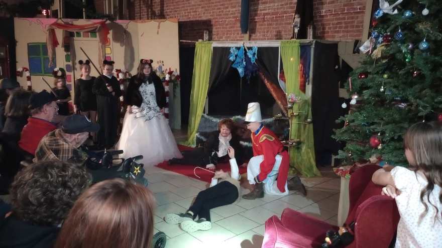 The Nutcracker kneels by the fallen performer as the scene plays out under the Christmas tree