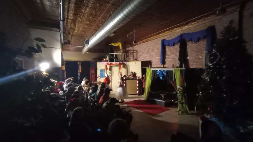 The darkened studio during the performance, the red carpet glowing under the stage lights