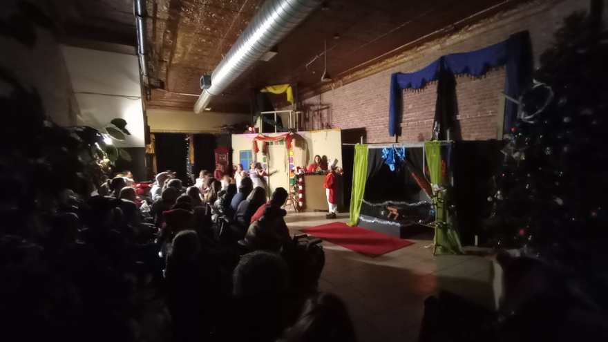 The audience watches in the dark as a scene plays on the holiday set