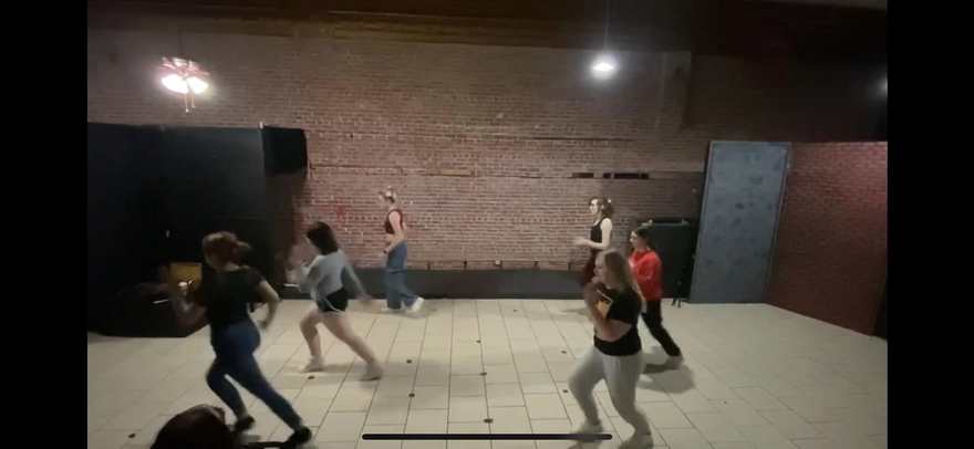 A wide view of the Firebringer cast rehearsing choreography across the studio floor
