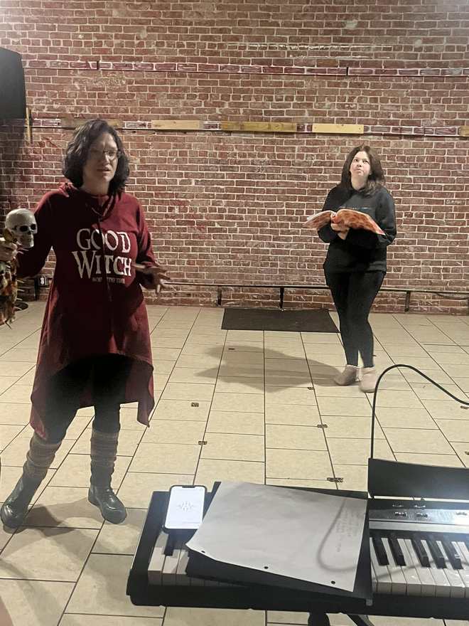 Two Firebringer performers rehearse a scene against the brick wall, keyboards in the foreground