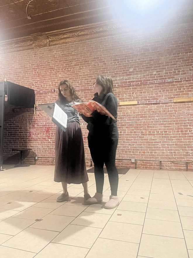 Two Firebringer performers face off in rehearsal, one holding an orange prop