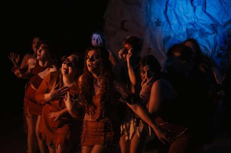 The Firebringer tribe reacts together in a dramatic firelit moment on stage